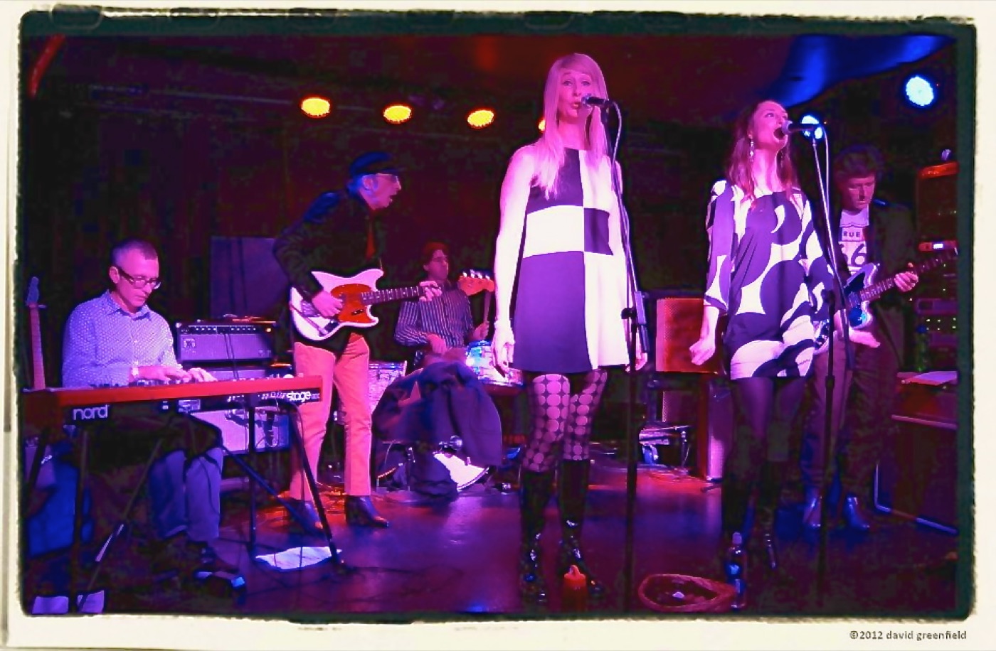 Two singers in black-and-white mod dresses at the microphones